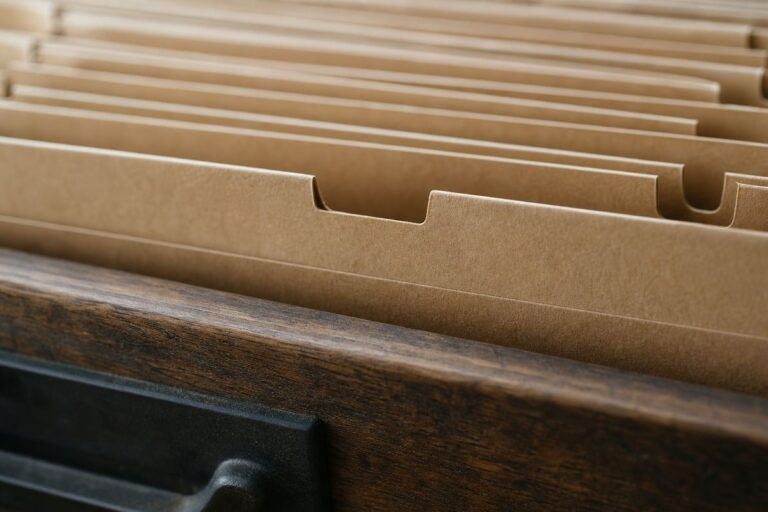 Kartonowe przekładki w drewnianej szufladzie, jedna wysunięta poza równą linię